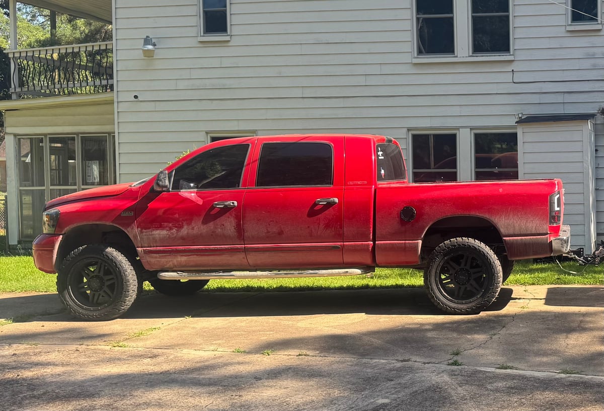 Red pickup truck with lifted suspension parked in front of a white house